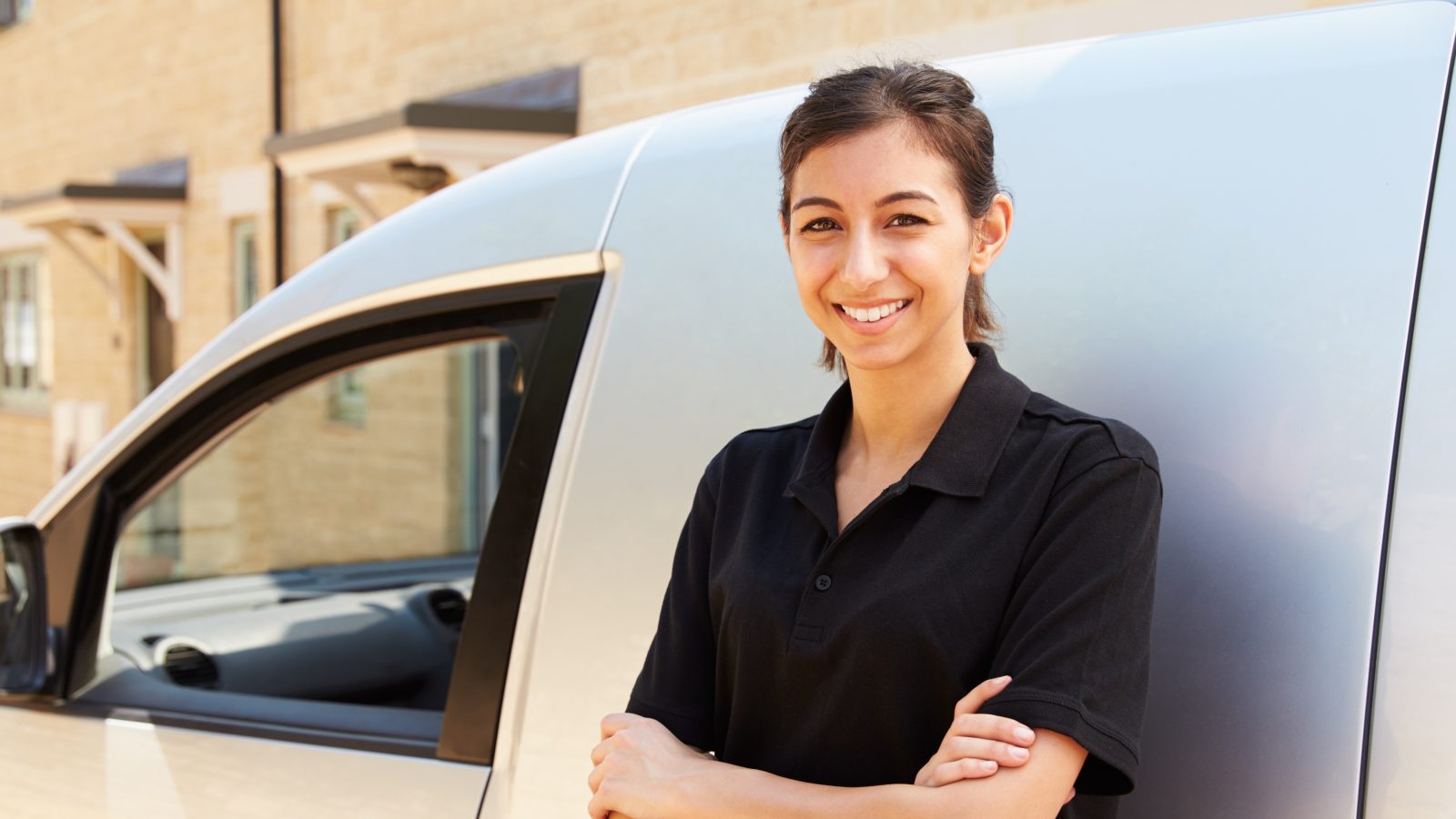 Portrait of young female worker standing by a van