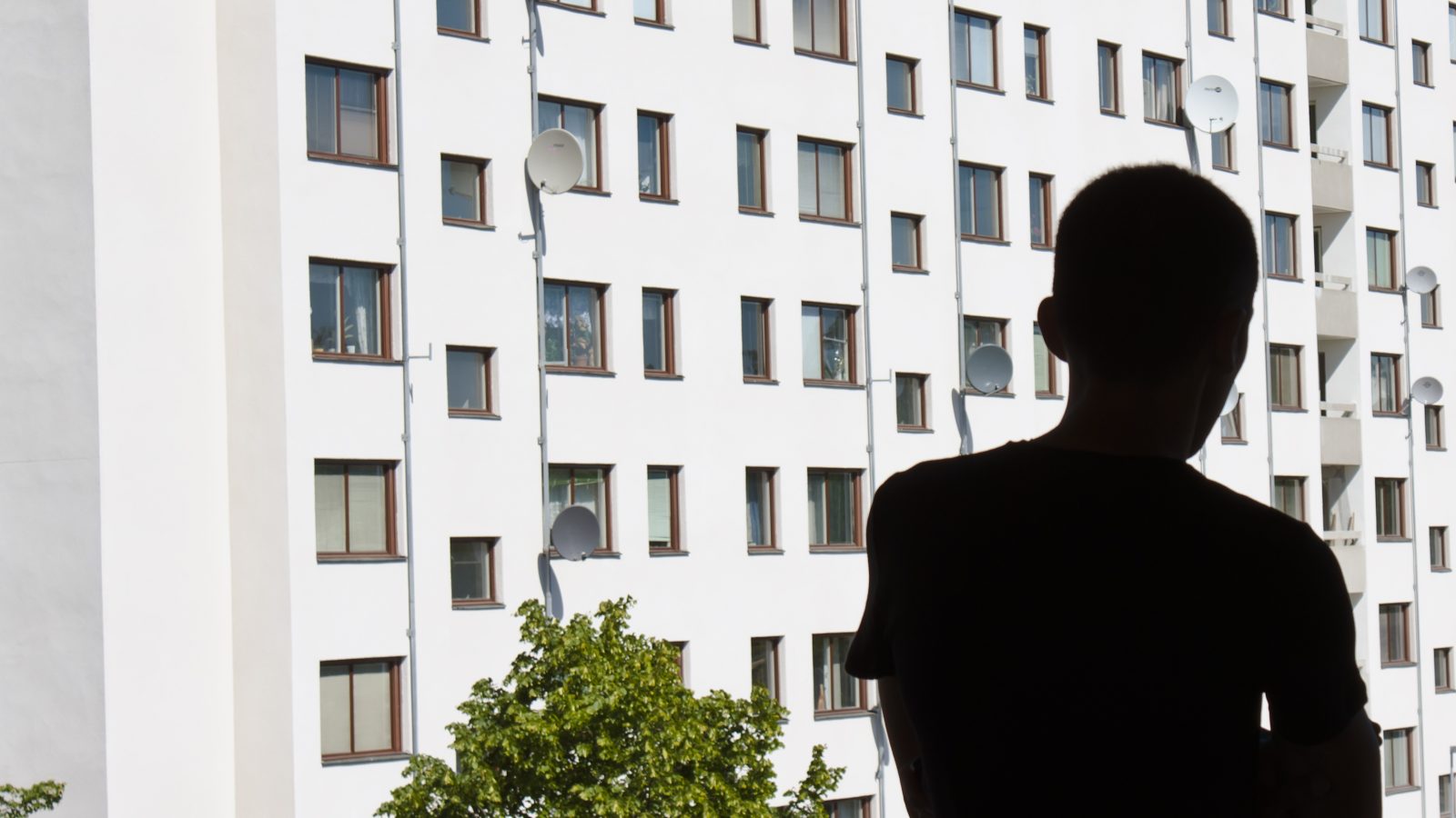 man sedd bakifrån i ett höghusområde