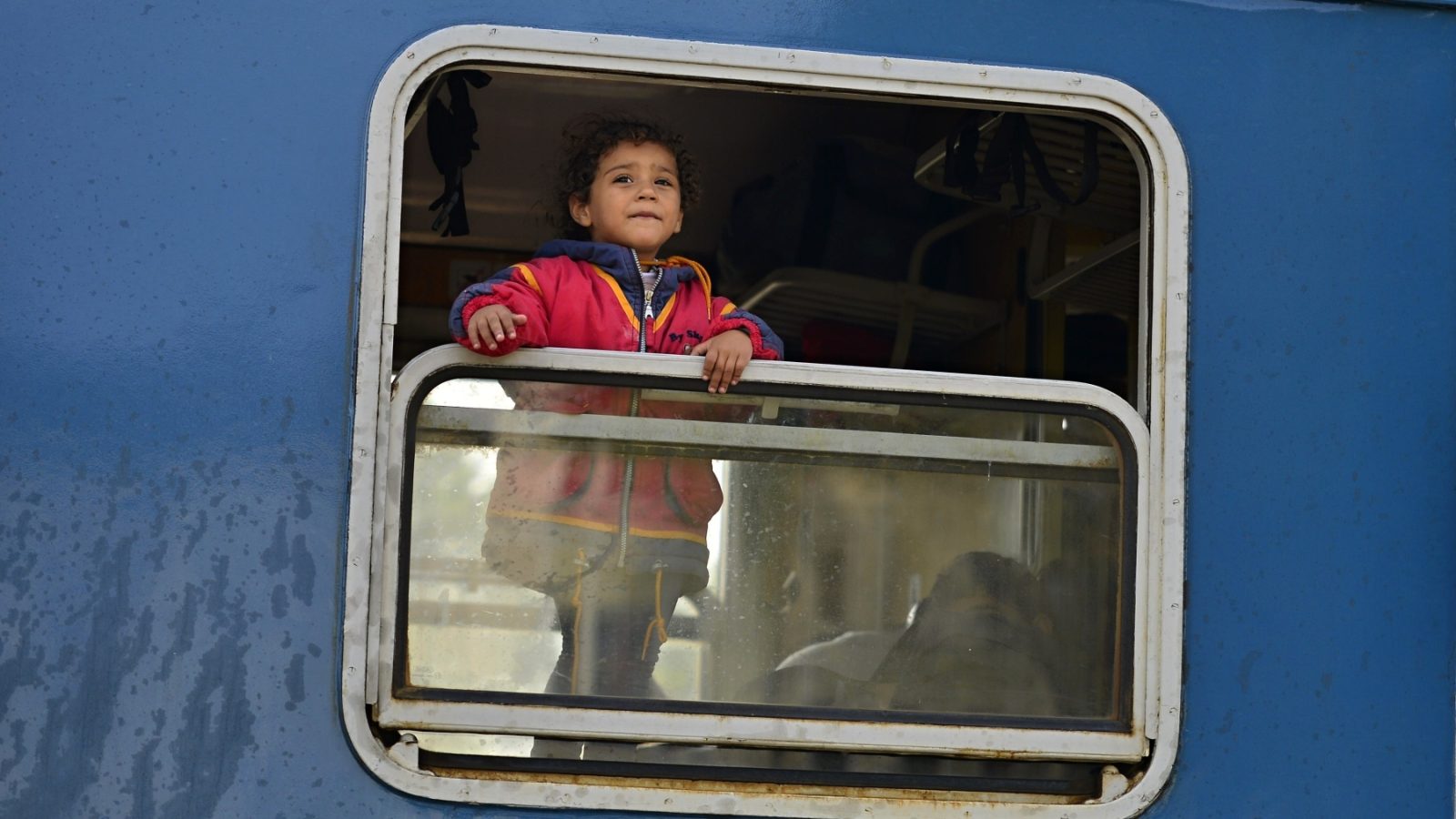 Small child looks out of a train window