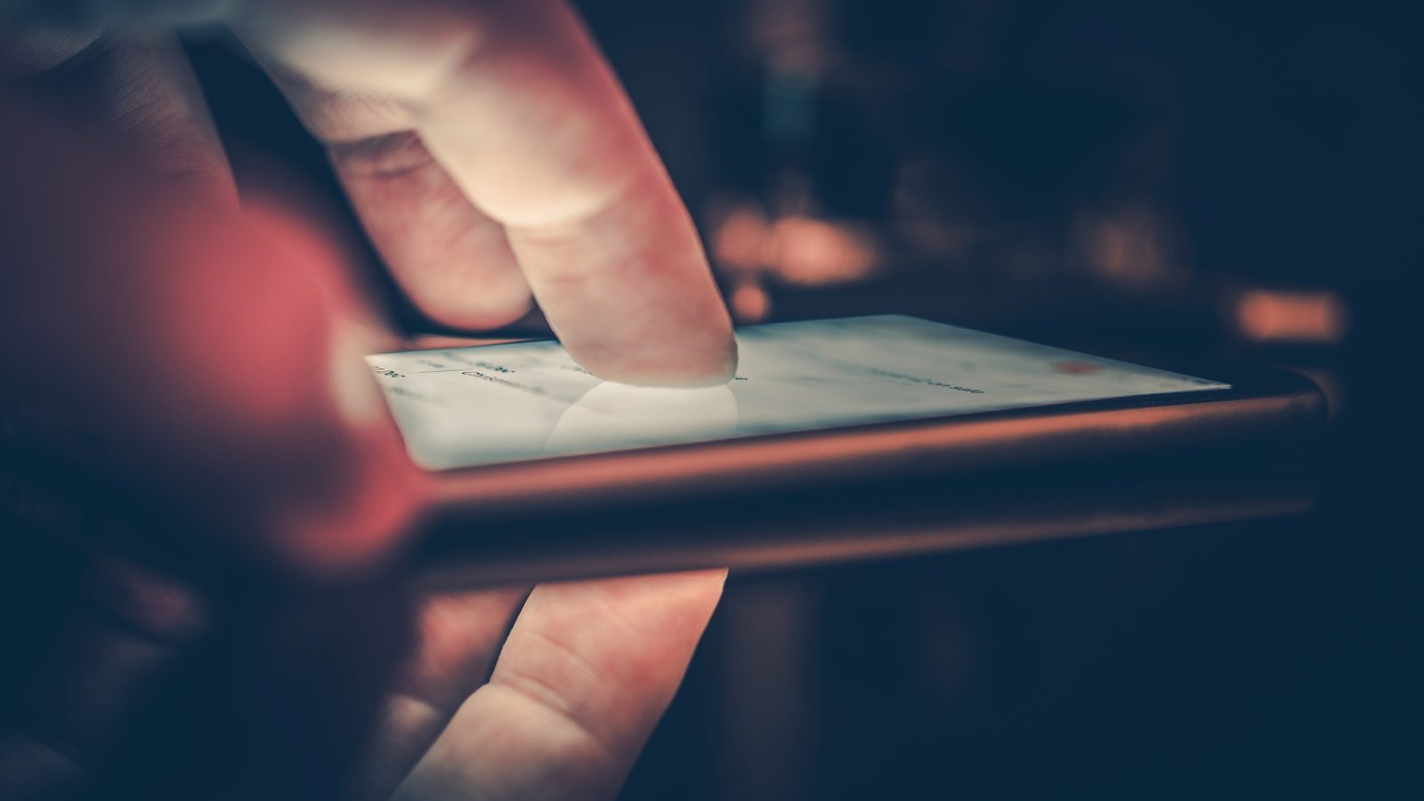 Närbild på ett finger på en smartphone i en mörk miljö