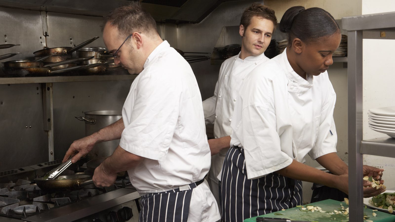 Tre personer som jobbar i ett restaurangkök