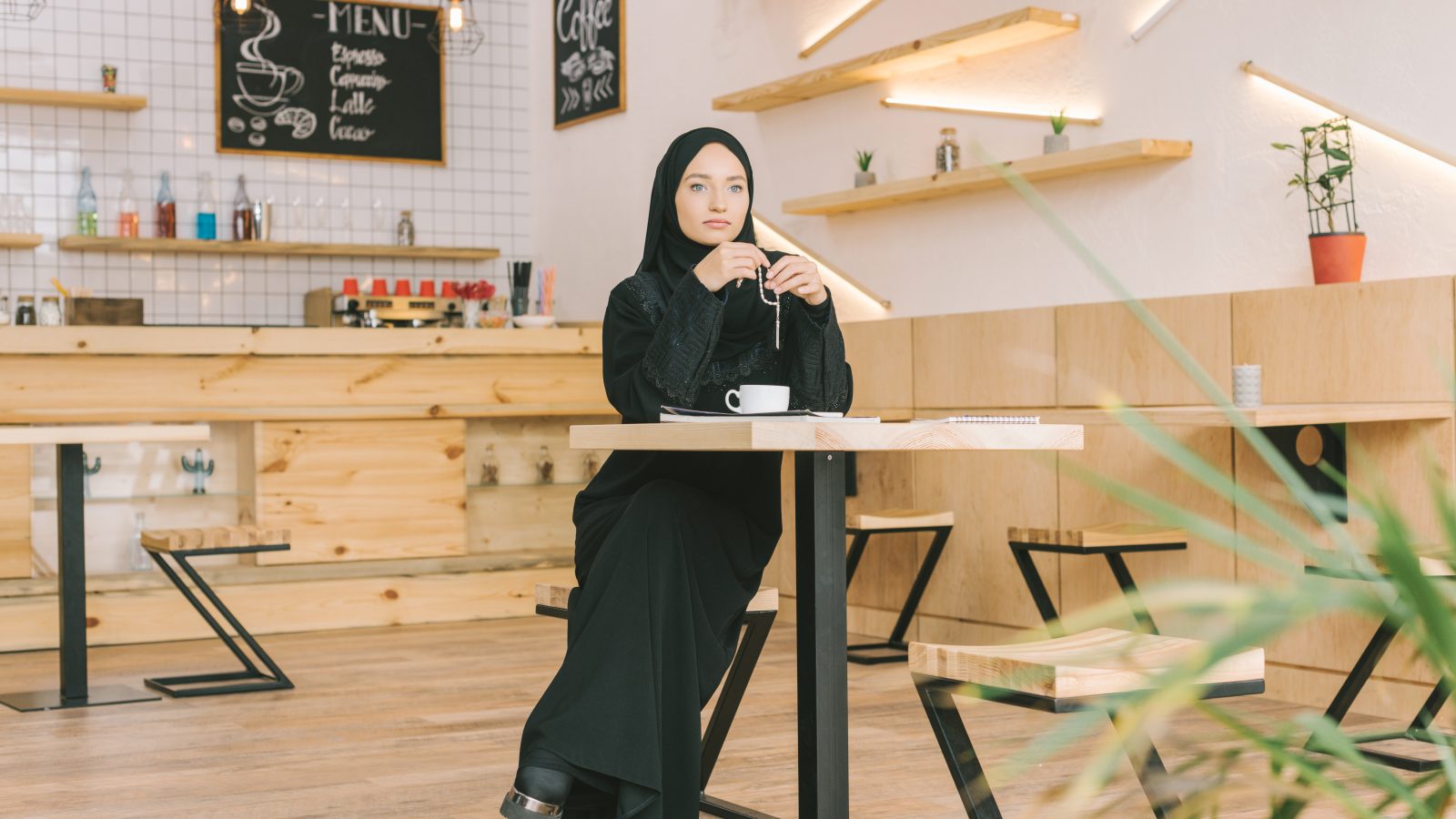Kvinna med hijab sitter på ett café.