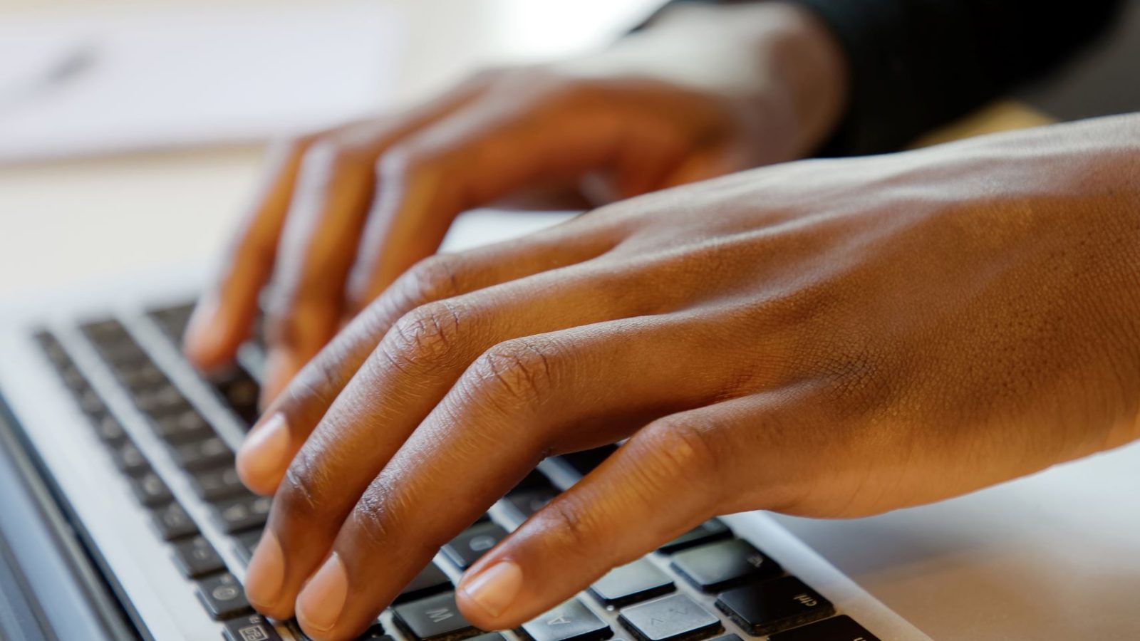 Närbild på händer som skriver på en laptop