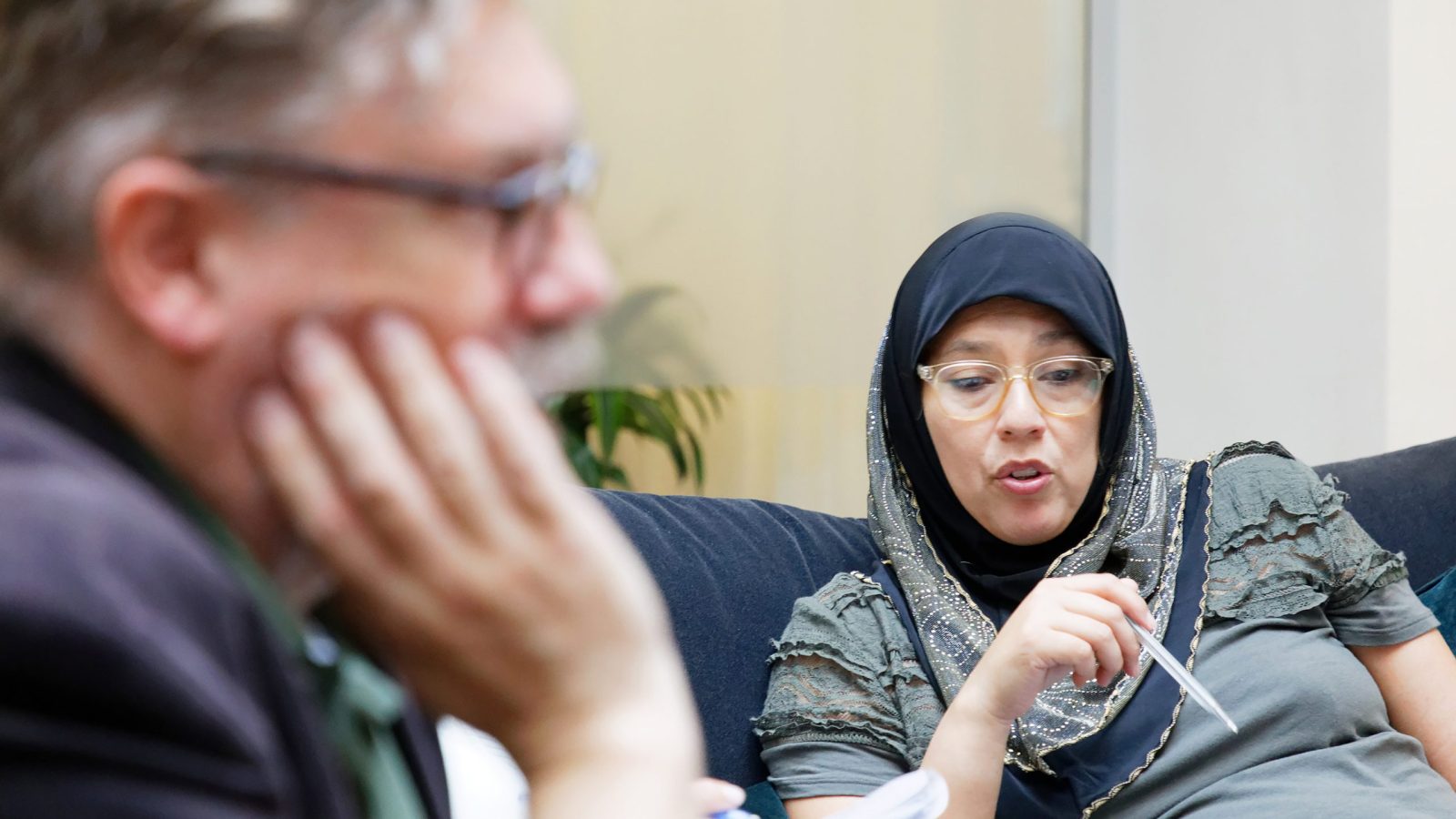 Kvinna iklädd slöja diskuterar med en manlig kollega