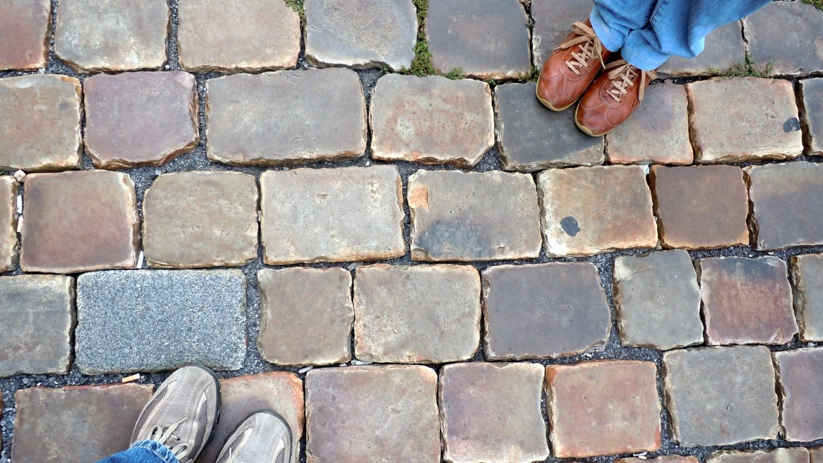 two couple of shoes stand over a stone ground
