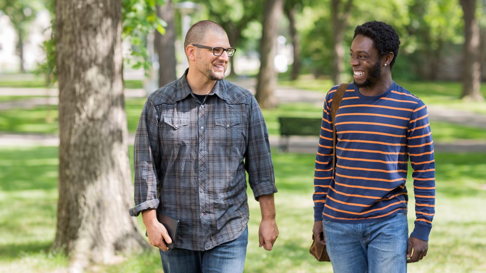 Happy male students communicating while walking on university campus