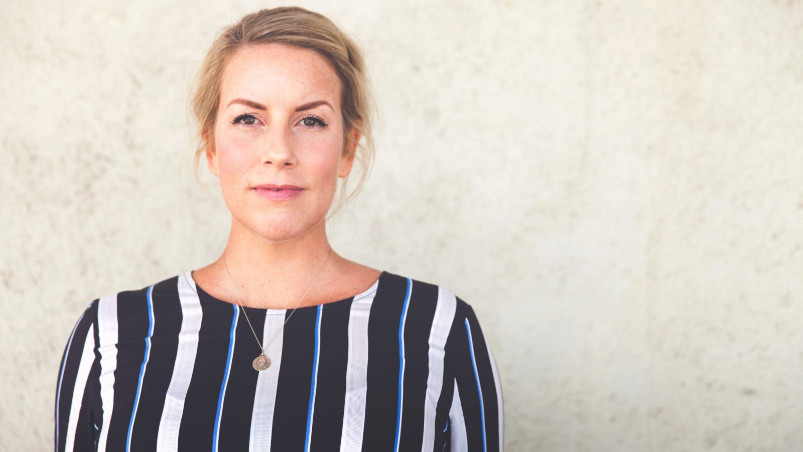 Foto av Linn Iren Engemyr Knutsen. Hon har blond upsatt hår och blå och vit-randig blus.