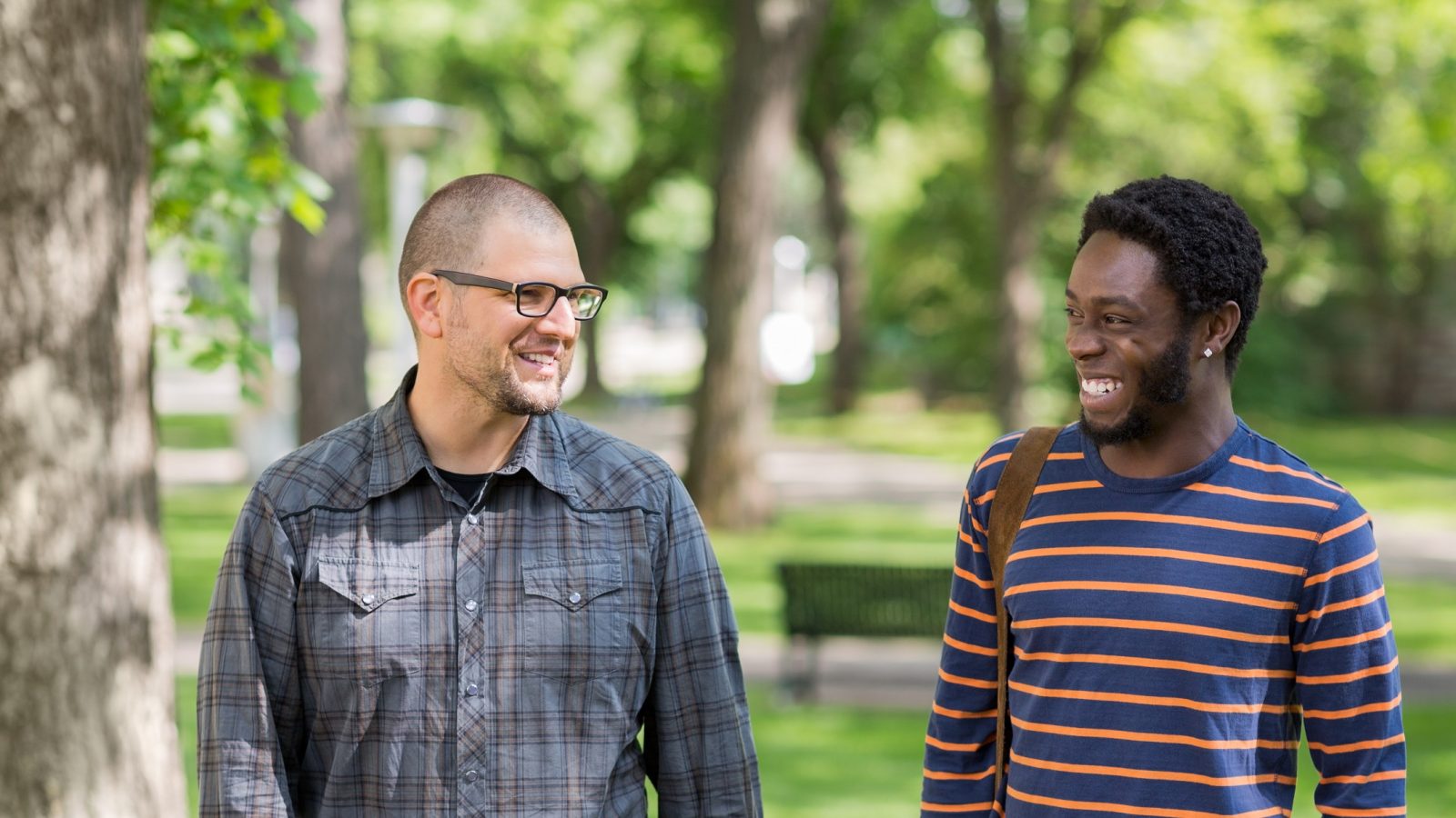 Happy male students communicating while walking on university campus