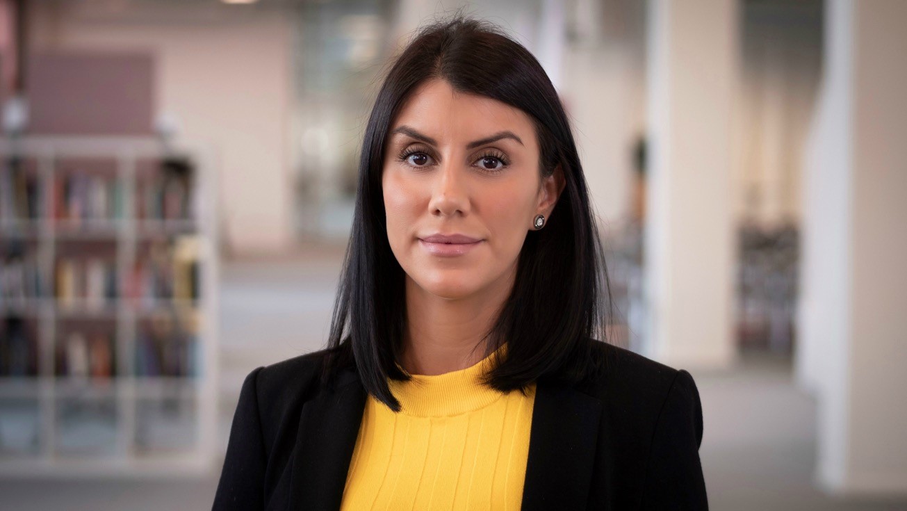 Foto av Negin taget framifrån. Hon har mörkt halvlångt hår och svart kavaj med gul blus under