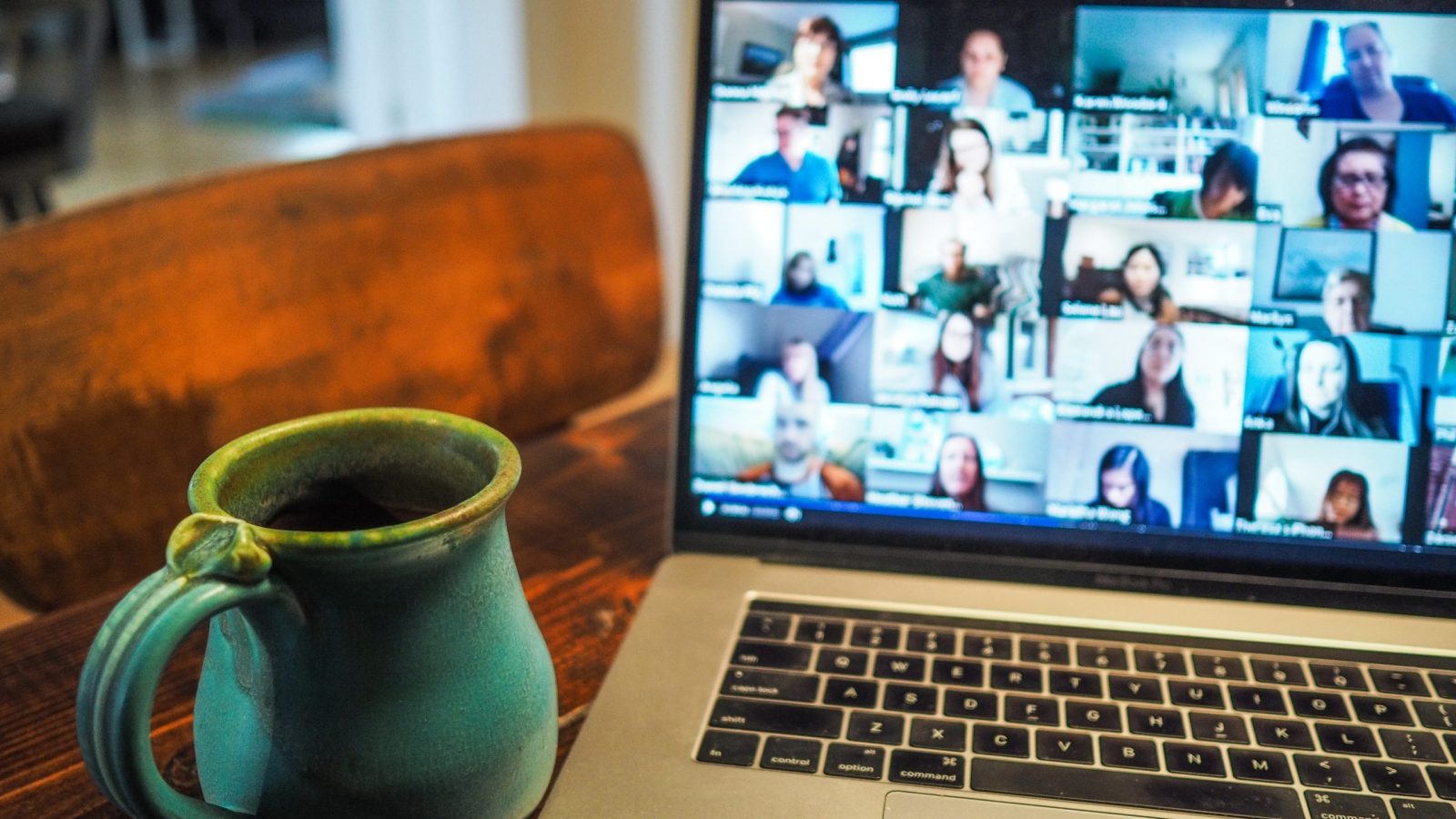Laptop med videomöte till höger i bild, till vänster en grön kanna och en brun stol