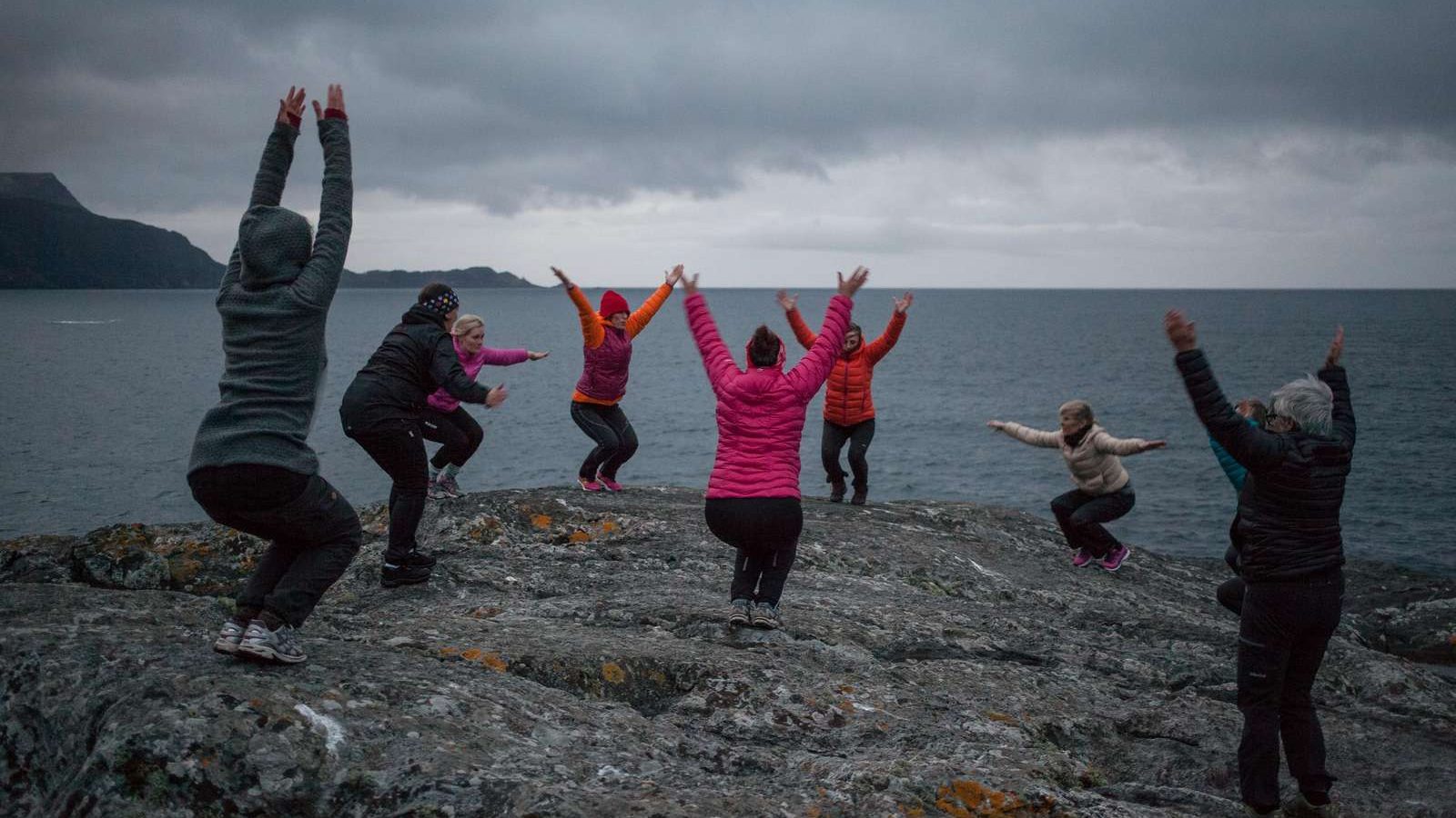 nio personer som yogar på en klippa i naturen