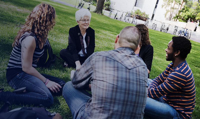 Senior female university professor teaching students outdoors