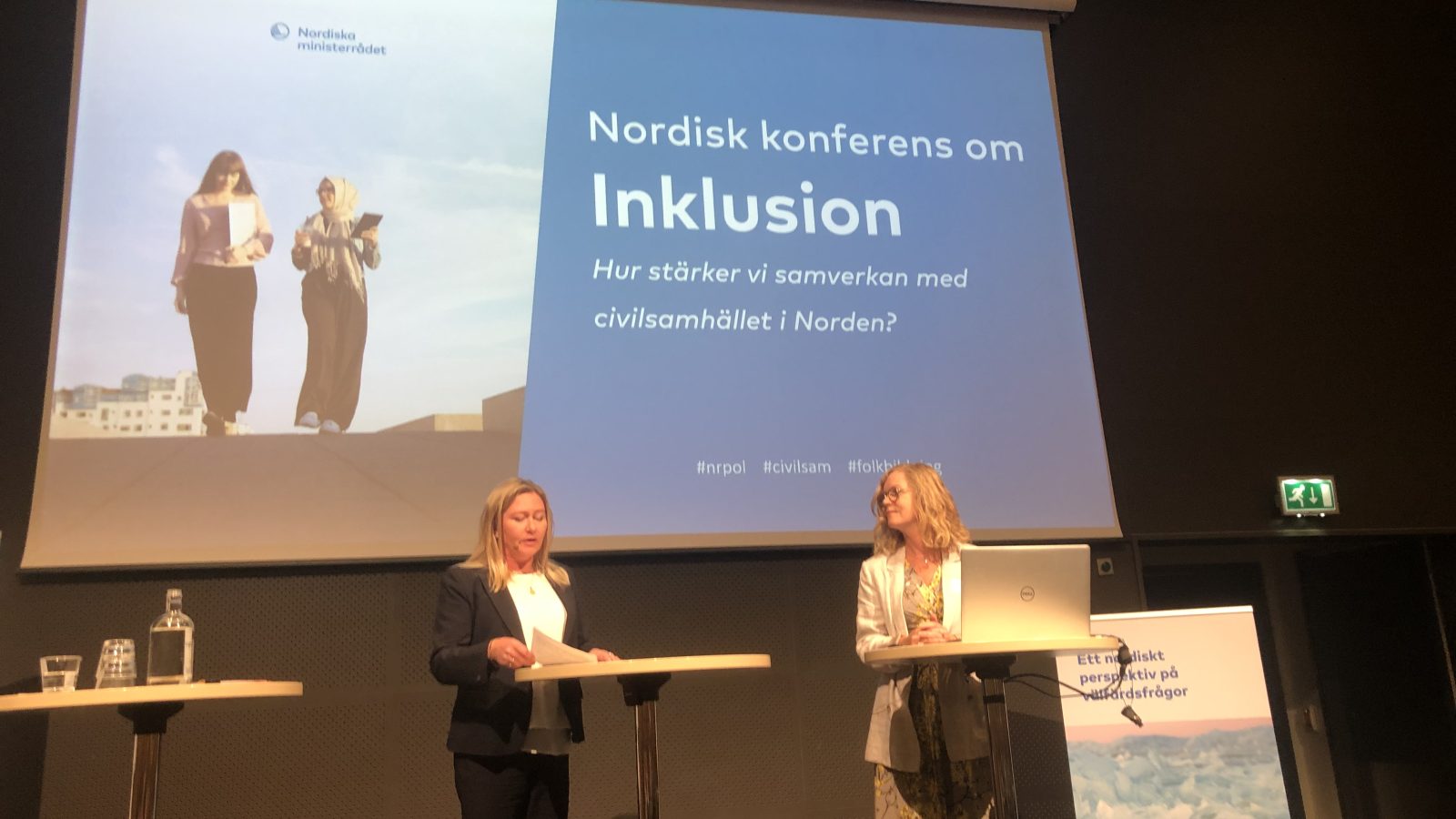 Två kvinnor samtalar på konferensscen