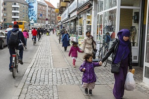 Vuxna och barn på trottoar och cykelväg i stadsmiljö