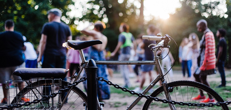 Cykel lutade mot stolpe med folk i bakgrunden
