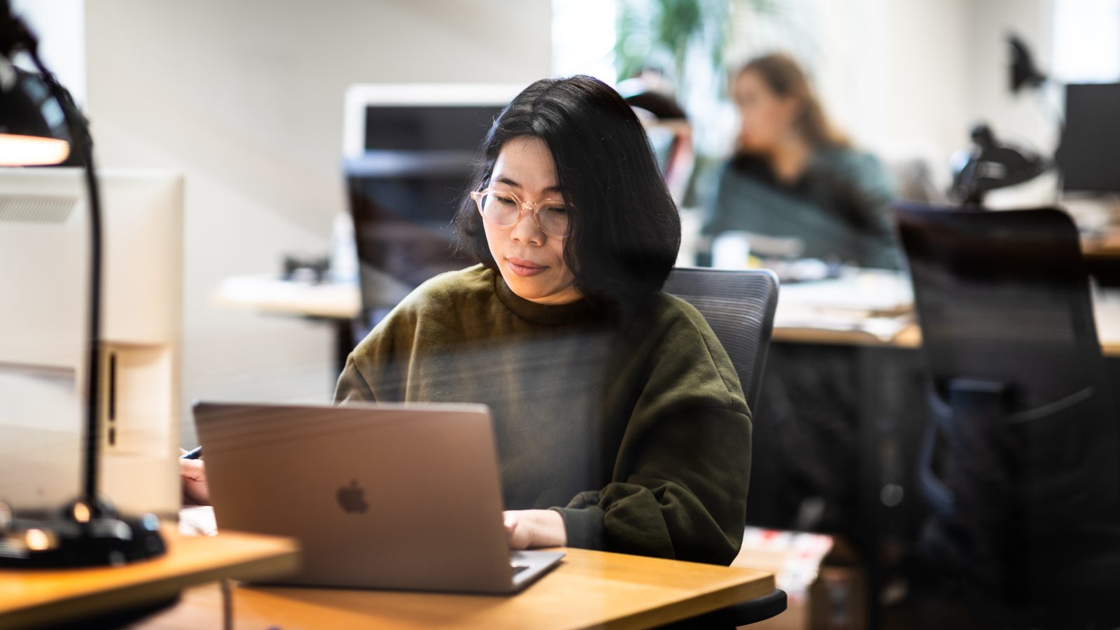 Asiatisk kvinna jobbar på laptop.