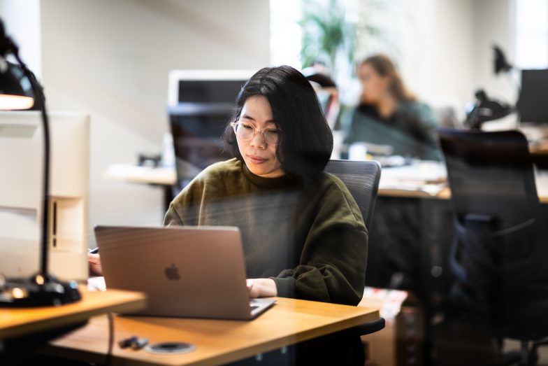 Asiatisk kvinna jobbar på laptop.